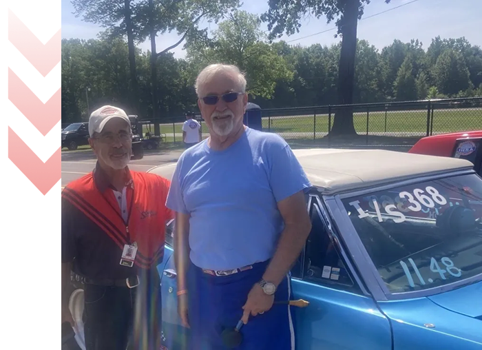 Two men standing by a classic car.